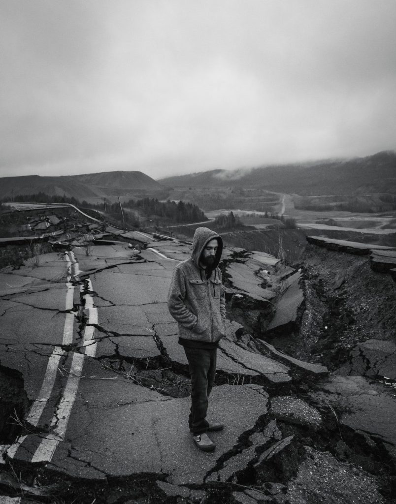black and white image of world crumbling around a man in hoodie due to Acute Trauma