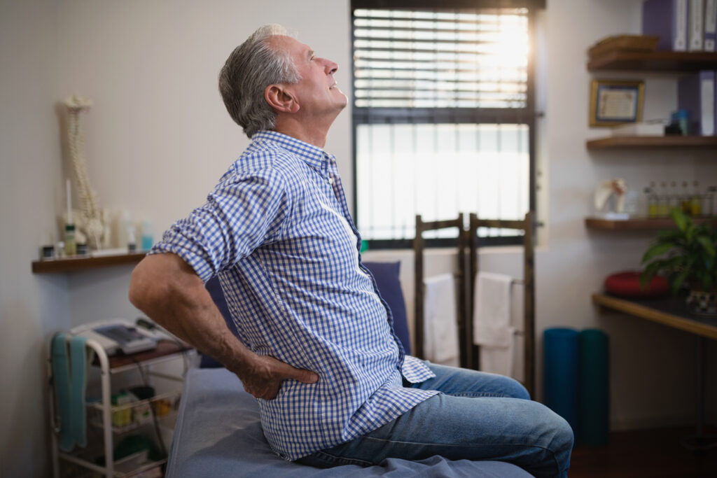 Side view of senior male patient suffering from back ache while looking up on bed
